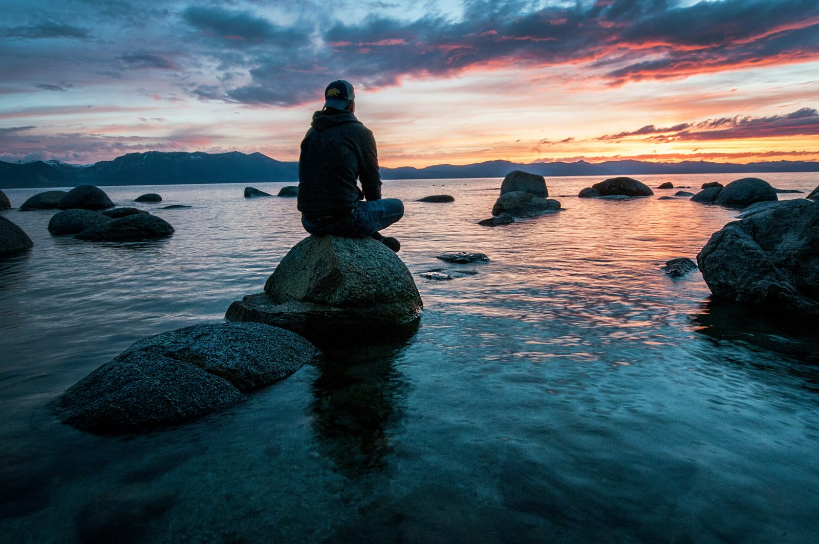 Man sitting alone at dusk, looking out over water, reflecting on anger and what's underneath it
