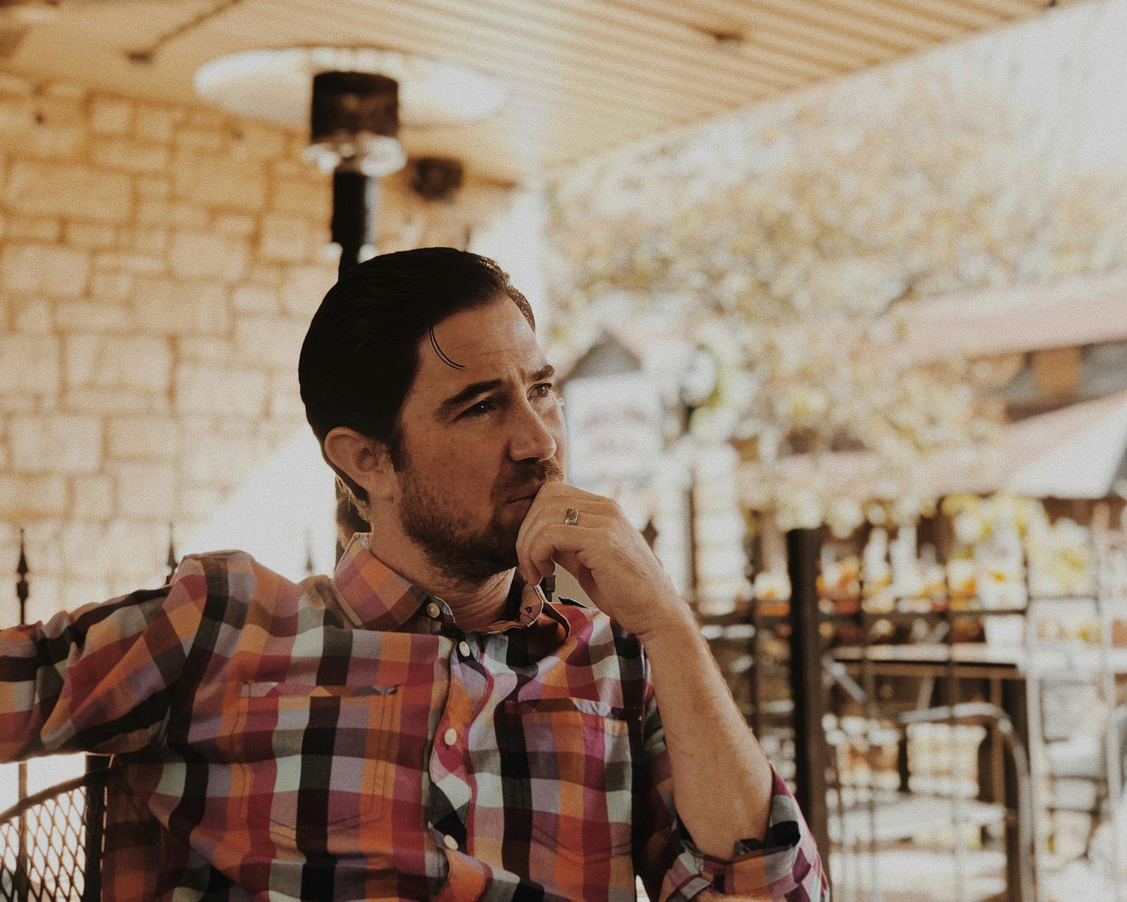 A pensive man in muted light considering the midlife "is this it" question, men's therapy in Ontario