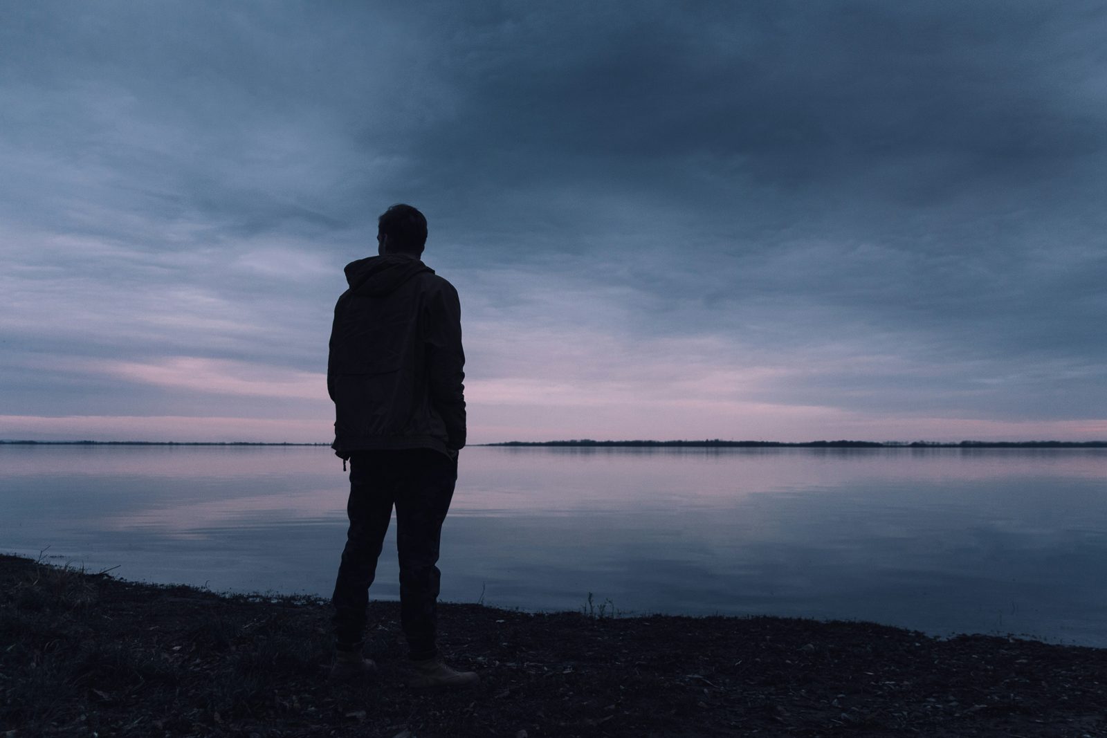 A man sitting alone by a window, looking downcast and reflective